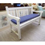 A modern white painted garden bench of slatted construction,