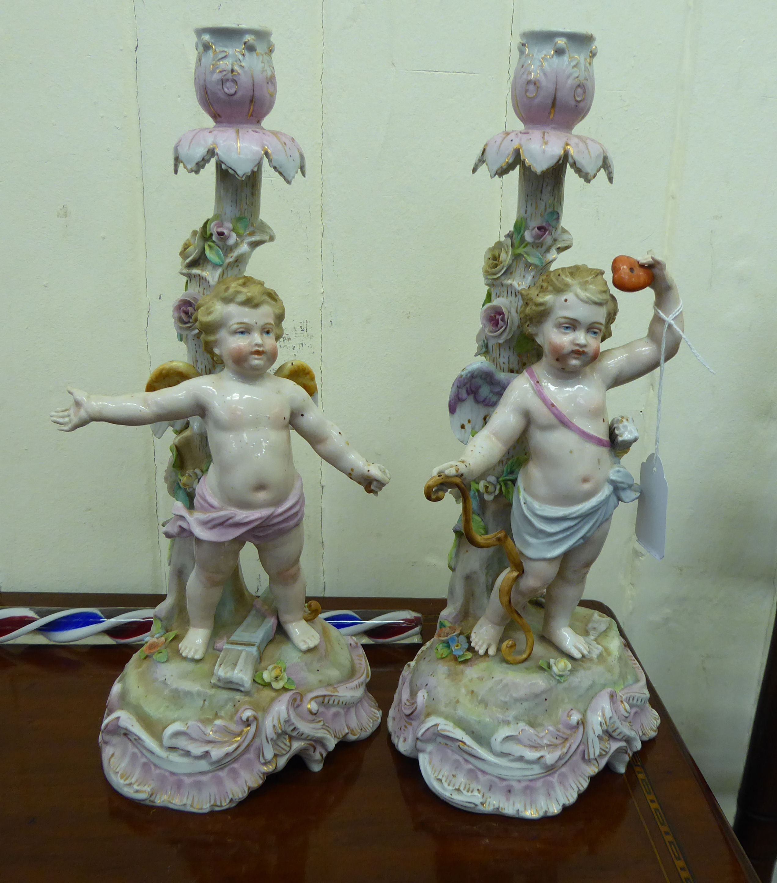 A pair of early 20thC German floral encrusted, painted porcelain candlesticks,