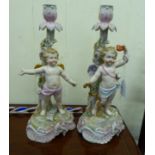 A pair of early 20thC German floral encrusted, painted porcelain candlesticks,