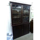 An early 20thC mahogany cabinet bookcase with a moulded cornice, over a pair of glazed doors,