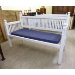 A modern white painted garden bench of slatted construction,