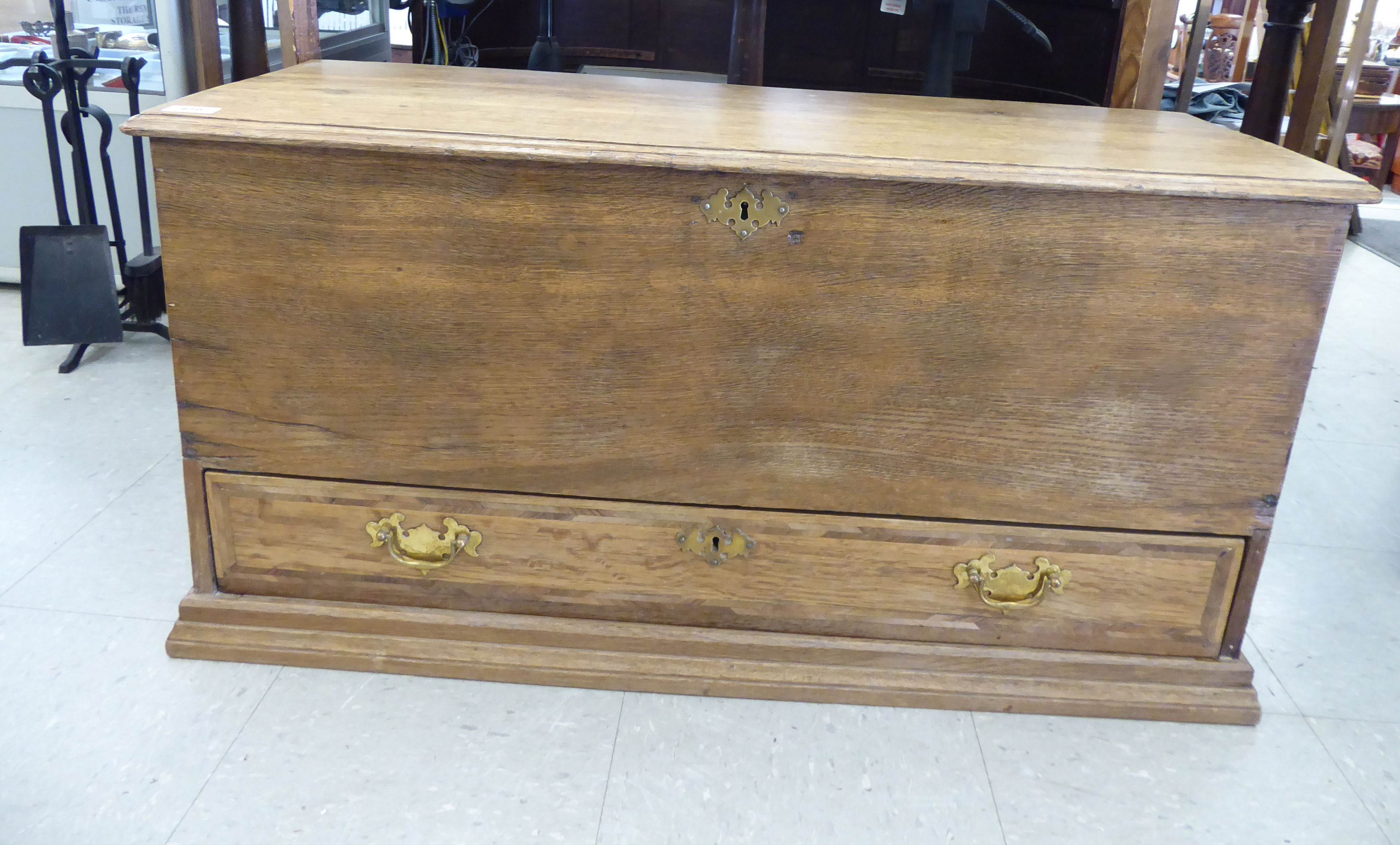 An early/mid 20thC pale oak chest with a hinged lid and straight sides, over a single long drawer,