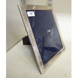 A glazed silver photograph frame, on a mahogany back and an easel stand London 1977 11.75'' x 9.