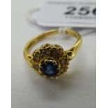 An 18ct gold cluster ring, set with a raised sapphire,