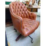 A mid 20thC desk chair, the part button and stud upholstered red hide back,