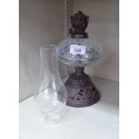 A late 19thC Arts & Crafts inspired oil lamp with a glass reservoir,