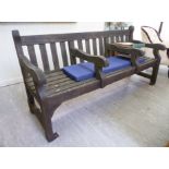 A modern stained teak garden bench of slatted construction,