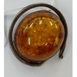 A brooch set with a central cabochon cut amber coloured stone,