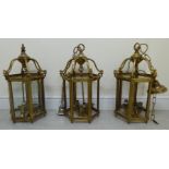 A set of three Georgian style, brass framed, hexagonal lanterns, on pendant chains,