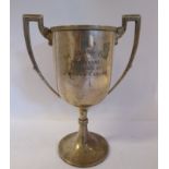 A silver trophy cup with a wire rim and angular handles,
