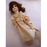 A late Victorian French doll with a porcelain head, painted features,