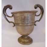 An Edwardian silver trophy cup with hollow C-scrolled handle, on a domed,