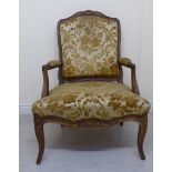 A late 19thC French Louis XV style stained, moulded and carved, showwood framed open arm chair,