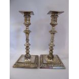 A pair of late Victorian loaded silver candlesticks of square outline with gadrooned ornament,