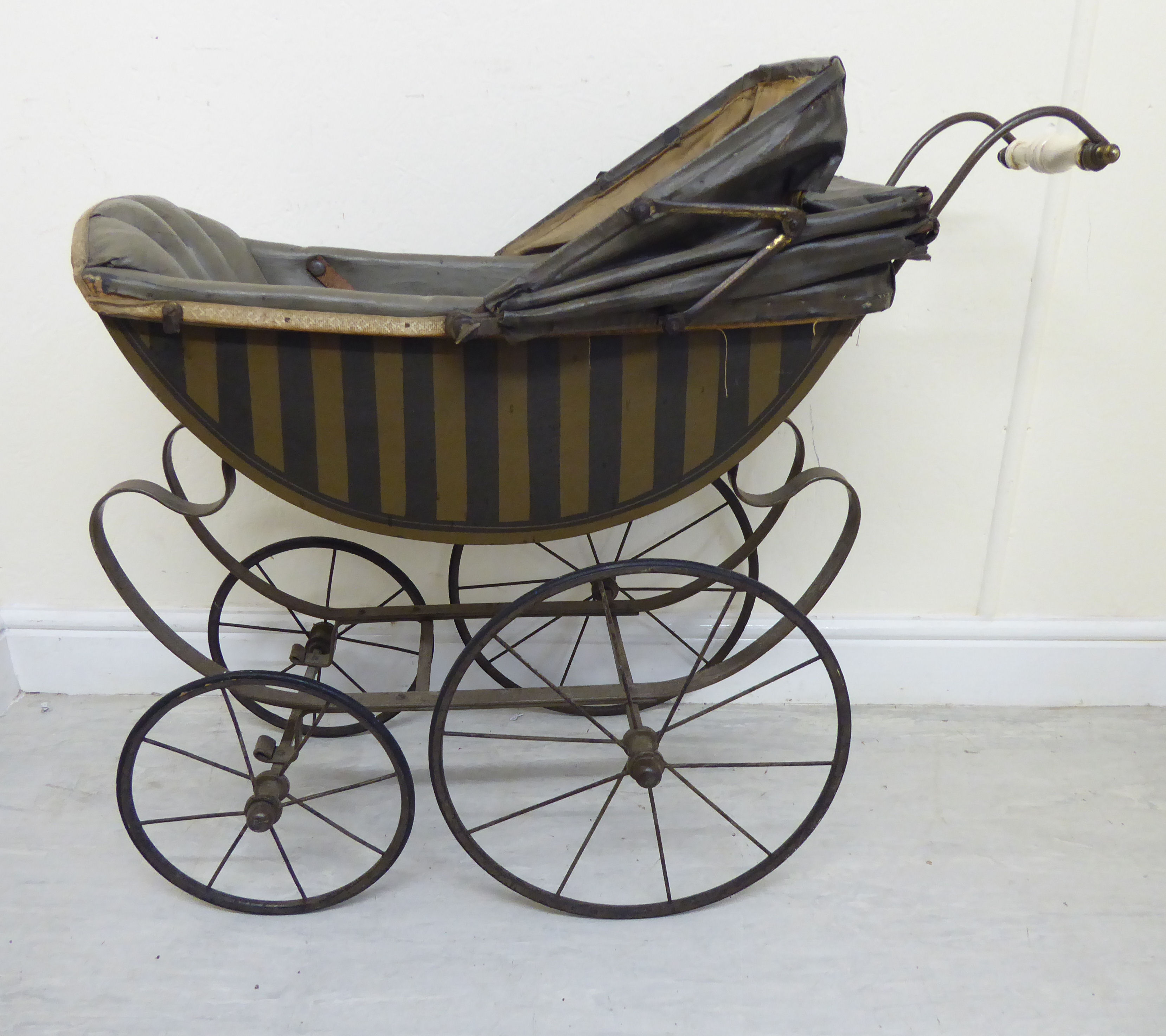 A late Victorian painted wooden dolls pram with a retractable canopy and a grey hide upholstered