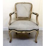 An early 20thC French limed and carved beech showwood framed arm chair with a stone coloured fabric