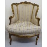 A late 19thC French moulded and carved giltwood, showwood framed chair with a high wing back,