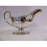 An Edwardian silver sauce boat with a wire loop handle and cast ribbon tied border,