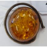 A brooch set with a central cabochon cut amber coloured stone,