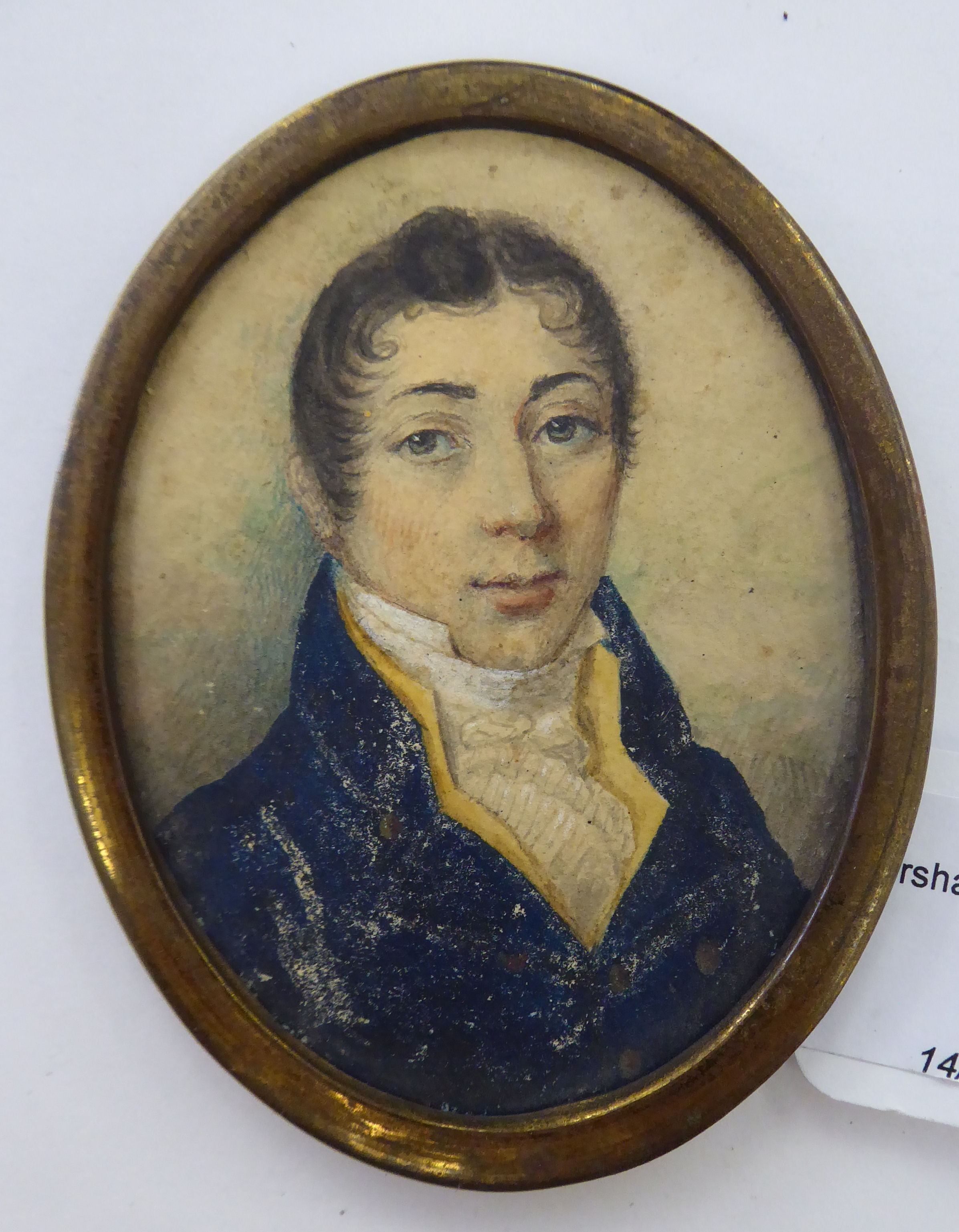 An early 19thC oval head and shoulders portrait miniature, a young man wearing a topcoat and cravat,