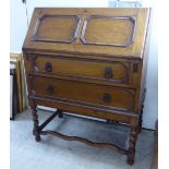 A 1920s oak bureau with a panelled fall flap, over two long graduated drawers,