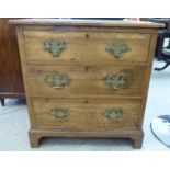 An early 20thC light oak chest, the three graduated long drawers with cast brass bail handles,