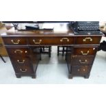 A mid 20thC mahogany finished nine drawer twin pedestal desk,