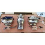 A three piece silver condiments set with blue glass liners;
