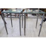 A pair of modern industrial style silvered steel lamp tables, each with a glass top,