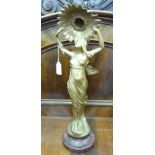 An Art Nouveau inspired gilded spelter table lamp, fashioned as a woman holding aloft a flowerhead,