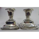 A pair of loaded silver dwarf candlesticks, each having a vase shaped socked,