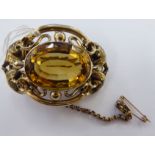 A gold coloured metal framed oval brooch, set with a citrine,