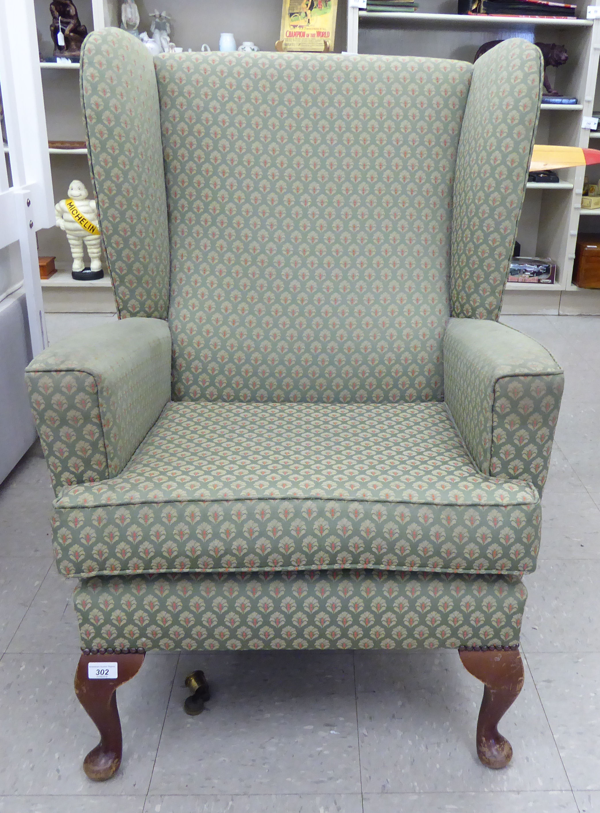 A mid 20thC wingback armchair, the fabric covered back,