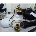 A brass oil lamp design pendant light fitting; an opaque white glass shade;