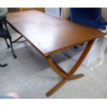 A modern teak coffee table, the top raised on a splayed crossover frame,