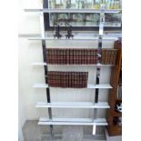A modern designer bookcase with six pairs of white painted metal platform shelves,