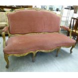 A late 19thC Continental carved giltwood framed settee with a round arched back and open arms on