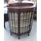A 1930s mahogany finished bow front display cabinet with a single door,
