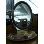 A late Victorian mahogany dressing table mirror, the oval plate pivoting on scrolled horns,