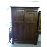 A 1920s stained oak wardrobe with a moulded cornice, over a pair of panelled doors,