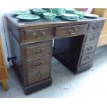 An early 20thC mahogany finished nine drawer twin pedestal desk,