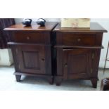 A pair of modern mahogany bedside cabinets, each with a single drawer and panelled door,