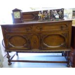 A 1930s oak sideboard with two drawers and two doors, raised on bulbous,