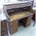 A 1930s oak roll-top desk, the serpentine tambour top enclosing a fitted interior, over twin,