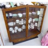 An Art Deco walnut finished display cabinet with an arched top, over a pair of glazed doors,