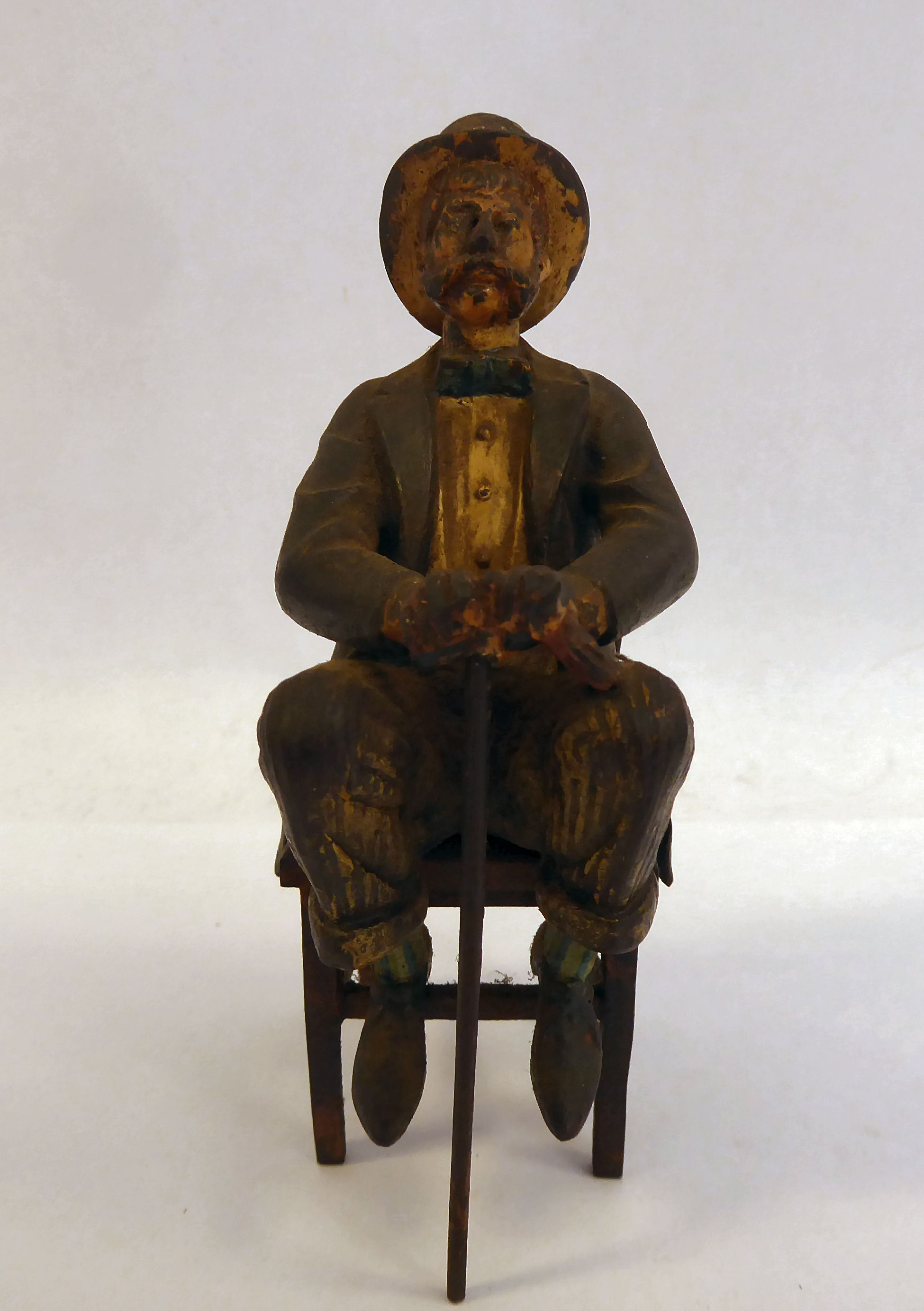 A late 19thC painted cold cast bronze figure, a bewhiskered gentleman, wearing a to hat and bow tie,