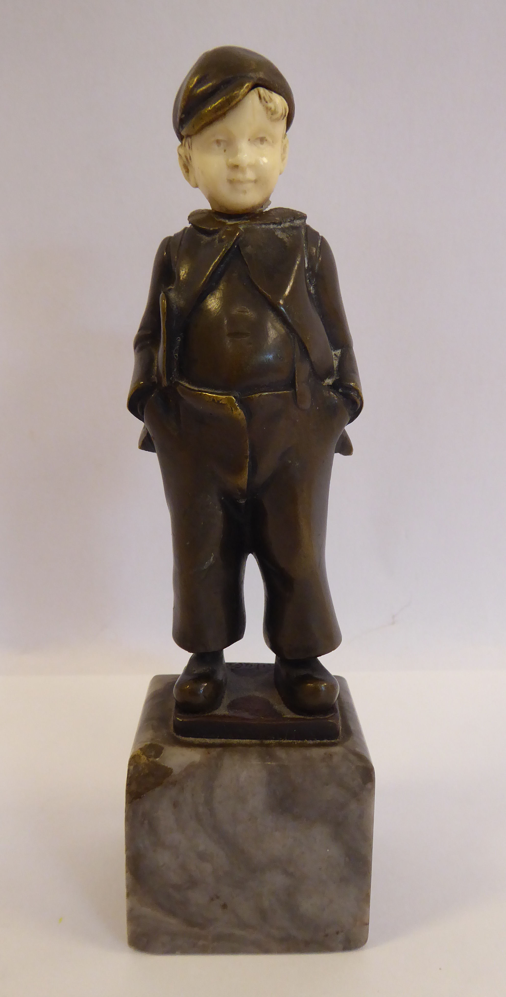 An early 20thC cast and patinated bronze and carved ivory figure, a Dutch boy, wearing a cap,