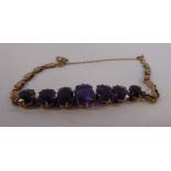 An 'antique' yellow metal bracelet, claw set with seven graduated amethysts,