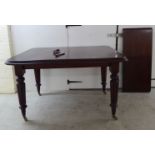 A mid Victorian mahogany wind-out dining table, the top with a thumb moulded edge and round corners,