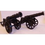 A pair of late 19th/early 20thC black painted iron model canons with 11''L barrels, on spoked,